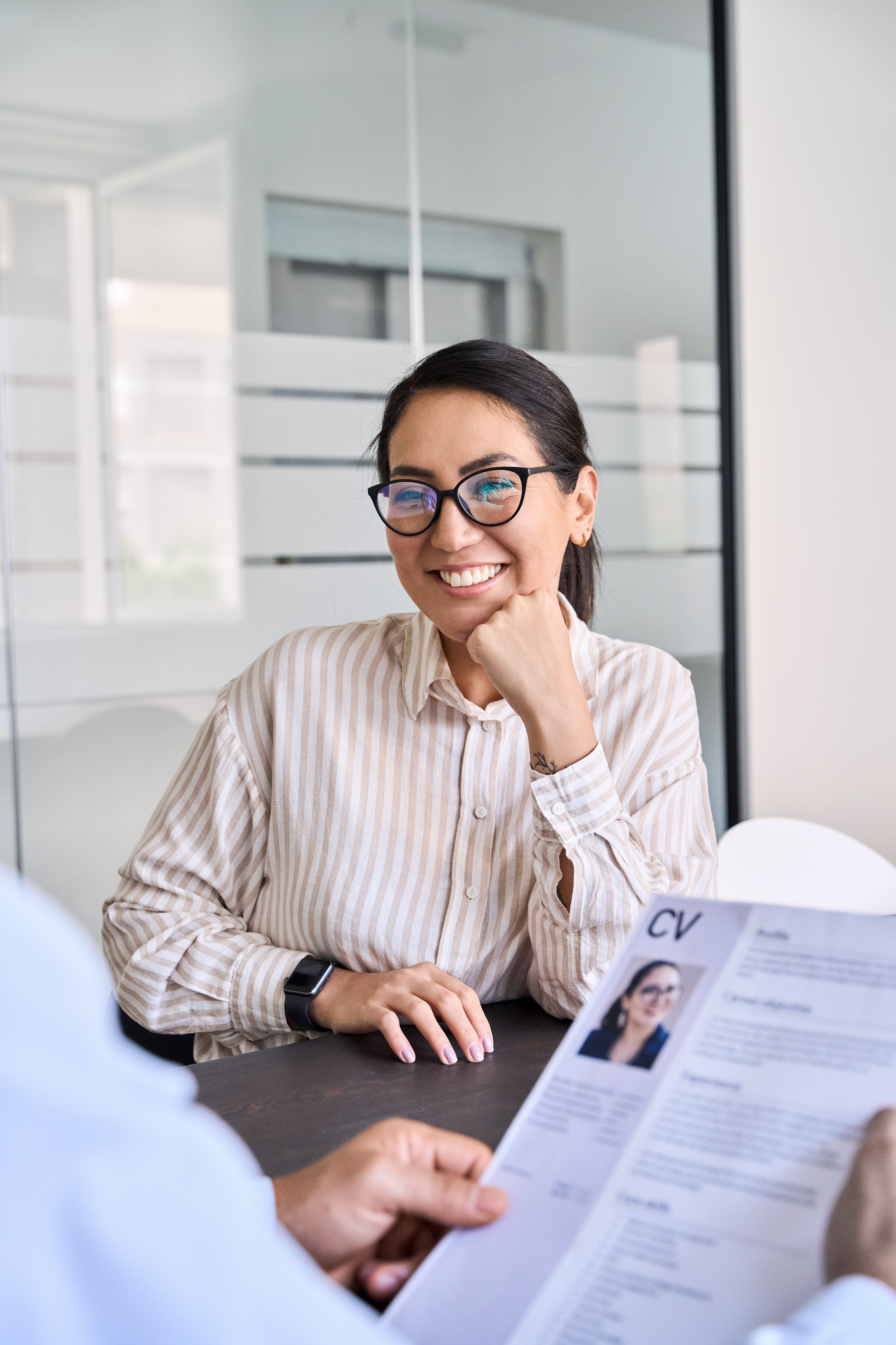 Smiling Asian woman candidate and hr manager holding cv during job interview.